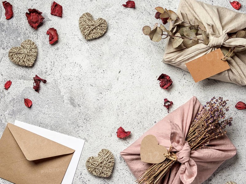 Zero waste Valentine's Day gift ideas concept. Eco-friendly gift cloth wrapping in Furoshiki style with dry lavender and eucalypt, craft paper envelope, greetings card on gray background, copy space