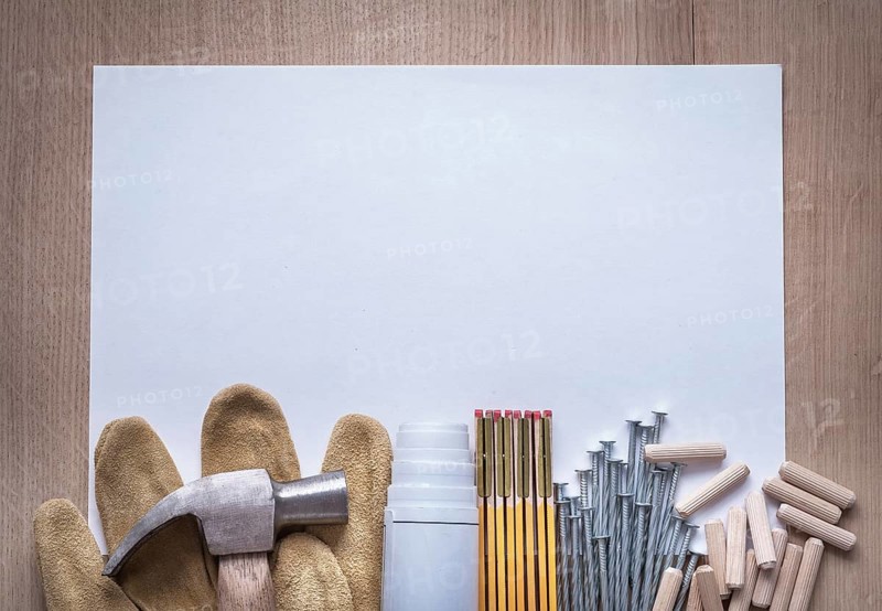 Wooden meter blueprints sheet of paper nails claw hammer fluted dowels and leather safety gloves on wood board copy space construction concept