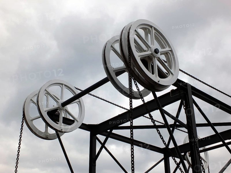 Wheels and pulleys on the historic canal chain bridge in Huddersfield West Yorkshire against grey clouds