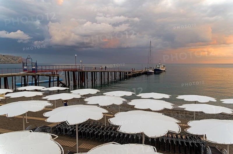 View of evening sunset sky from the empty beach of the resort town of Sudak. Crimea
