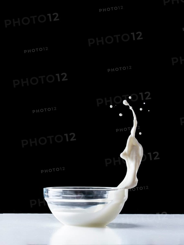 Glass bowl with milk or yogurt splash. Healthy breakfast ingredient. Flying food
