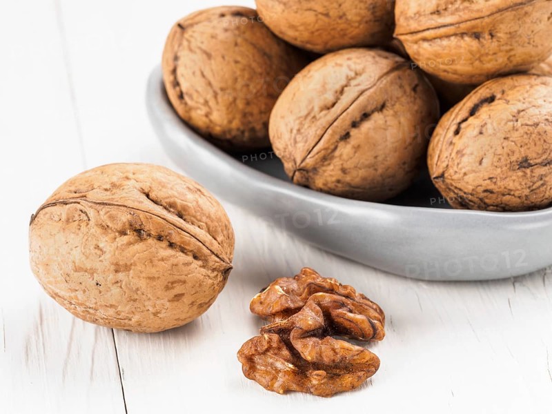 Inshell walnut on white wooden background