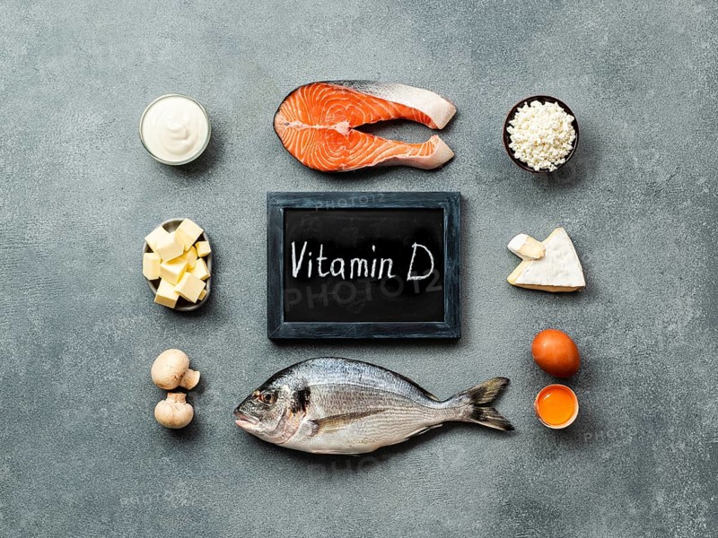 Vaitamin D sources concept. Fish, salmon, dairy products, eggs, mushrooms and chalkboard with Vitamin D words on gray stone background. Top view or flat lay