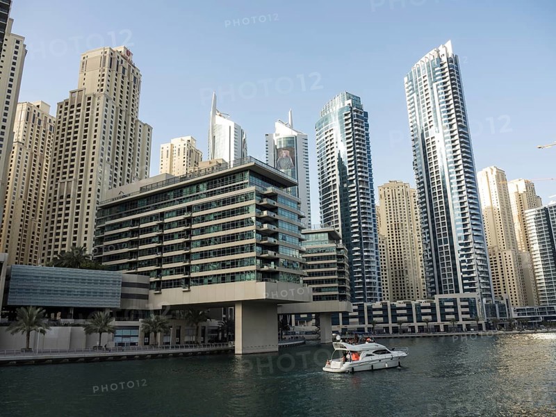 Modern skyscrapers on the riverbank with a boat on the water, impressive skyline of a modern city with spectacular skyscrapers, dubai, arab emirates