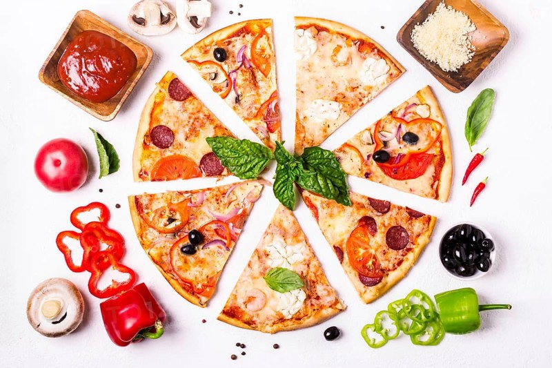 Selection of Assorted pieces pizza on white background and ingredients. Pepperoni, Vegetarian and Seafood Pizza