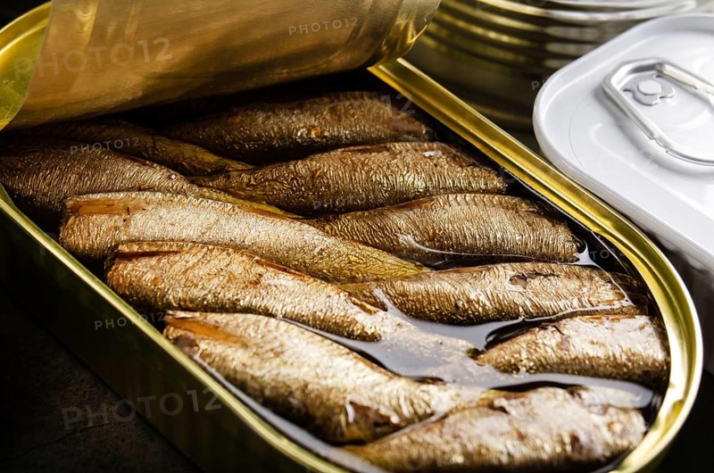 Canned smoked fish sprats in just opened tin can. Non-perishable food