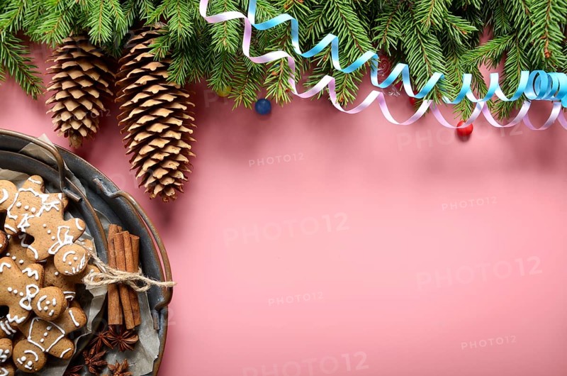 Flat lay design of Christmas greeting card of fir twigs cones party streamer and vintage metal tray with gingerbread man cookies on pink background. Space for text
