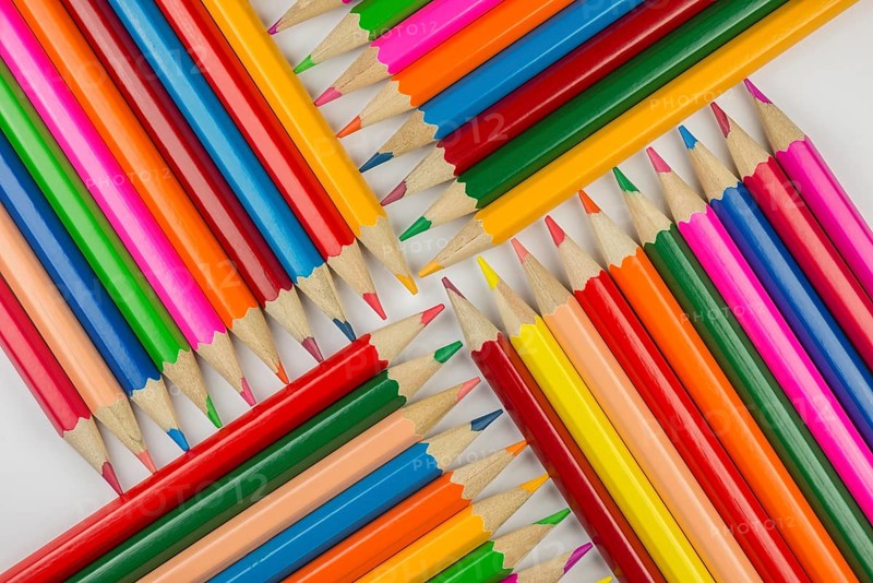 Abstract composition of a set wooden colour pencils against a white background