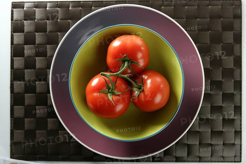 Three red tomatoes in the same one branch over green plate