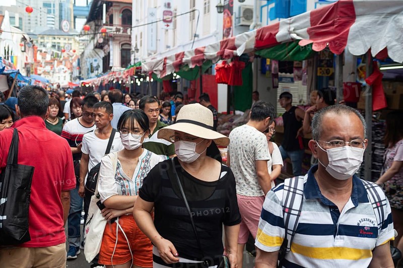 24.01.2020, Singapore, Republic of Singapore, Asia, Pedestrians wearing face masks stroll through a busy street bazaar in the Chinatown district, which takes place every year for Chinese New Year. This comes shortly after the first coronavirus infection was confirmed in the city-state
