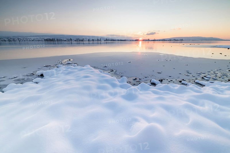 Winter landscape with a frozen lake at sunset, soft snow cover and reflecting water, Seegarten, Allensbach, Lake Constance, Baden-Württemberg, Germany