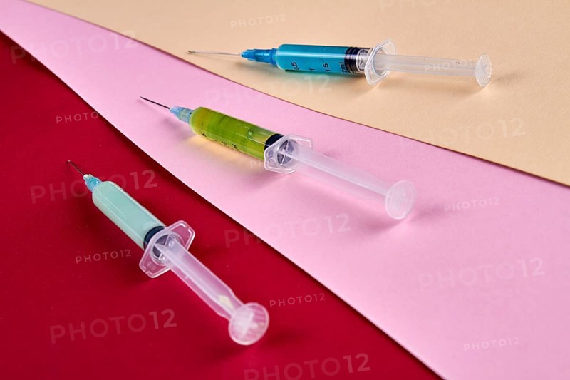 Close-up three syringes filled with multicolored medicine liquids. Drugs addiction and injections concept