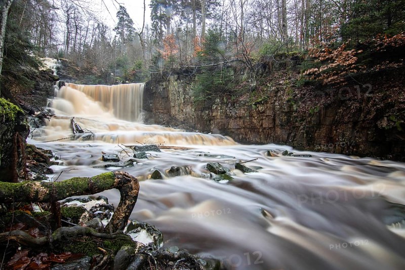 Landscape shot of a large waterfall in a spruce and birch forest and in nature. Autumn landscape with a river becoming the Byklevsfallet waterfall. Vänersborg, Sweden, Scandinavia