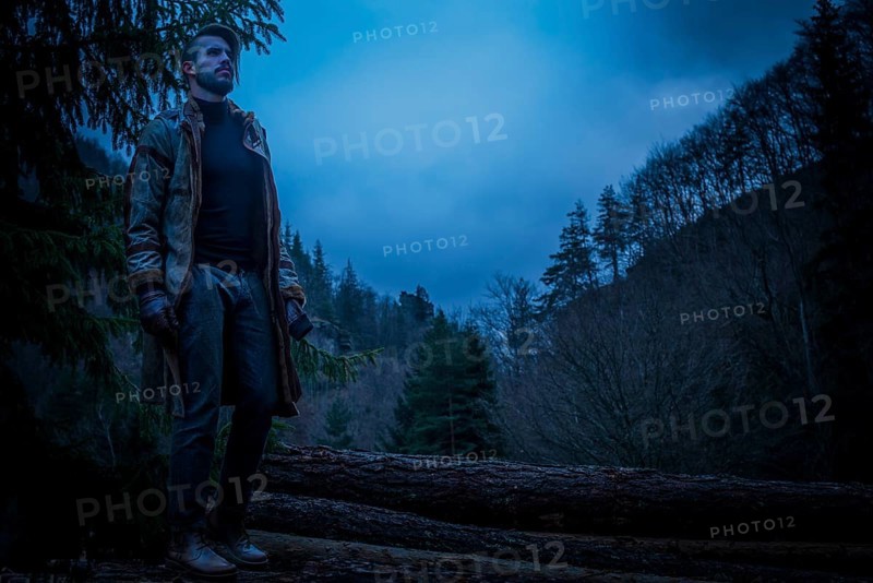 Young man in the forest at night. Early morning