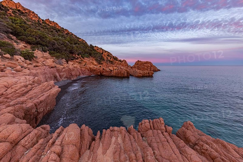 Large red rocks at the edge of the sea under a cloudy evening sky, Spiaggia di Cala E'Luas, Ogliastra, Sardinia, Italy