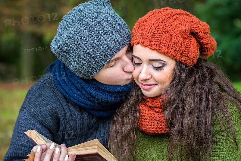 Loving couple reads a book in the autumn garden