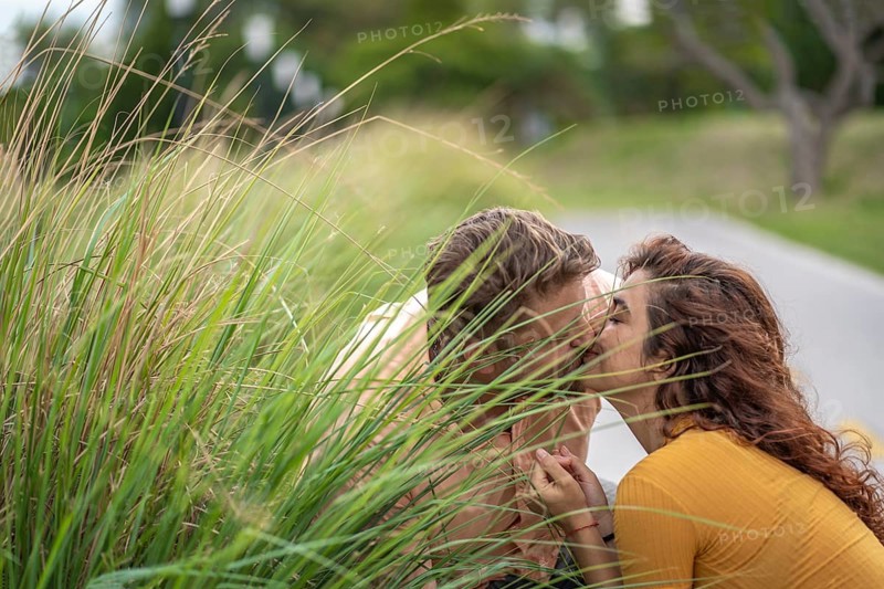 Couple secretly kissing behind a bush in a park
