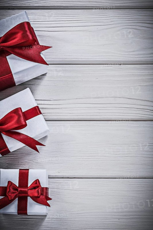 Present boxes with red bows on wooden board holidays concept