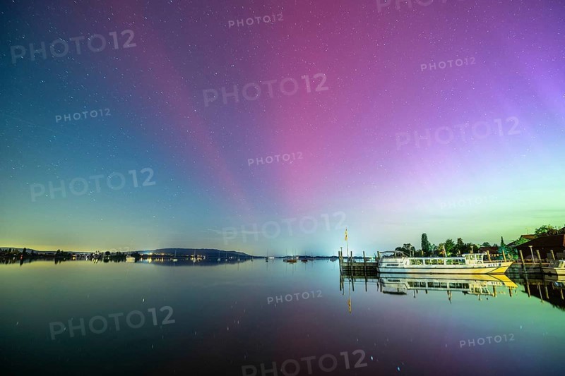 Calmness of the lake at night with starry sky, northern lights and a boat in the background, harbour, Allensbach, Lake Constance, Baden-Württemberg, Germany