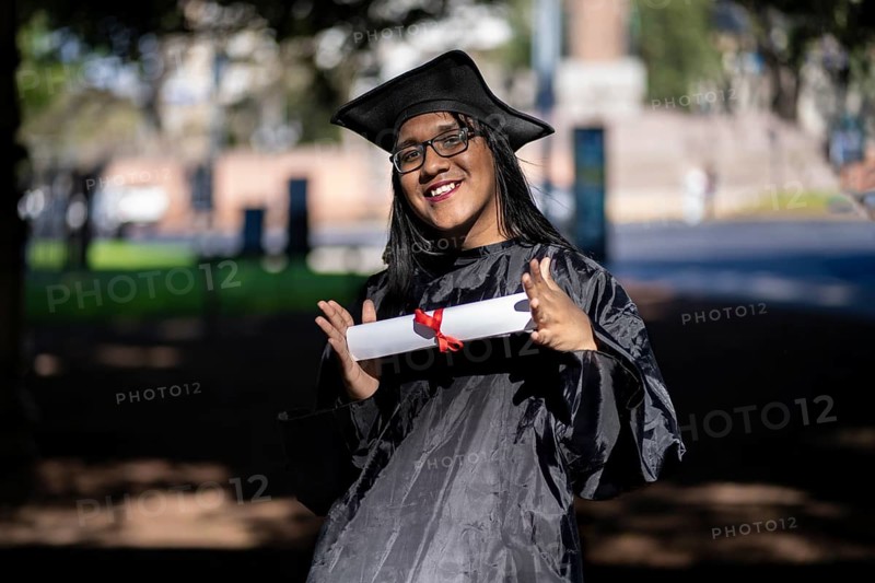 Latin transgender woman recent graduated, dressed in cap and gown, showing off his degree celebrating