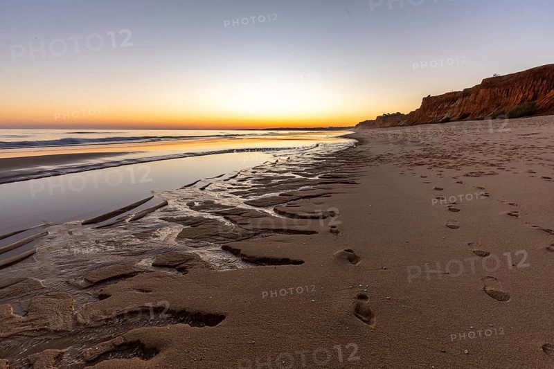 What a sandy beach on the Atlantic. Landscape shot at sunset on a coast with sandstone cliffs. Low tide on the yellow beach of Praia da Falésia near Albufeira, Algarve, Portugal