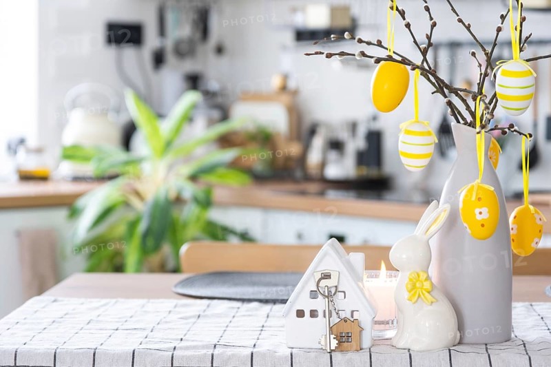 Key to house of cozy home with Easter decor with rabbit and eggs on table of kitchen. Building, design, project, moving to new house, mortgage, insurance, rent and purchase real estate