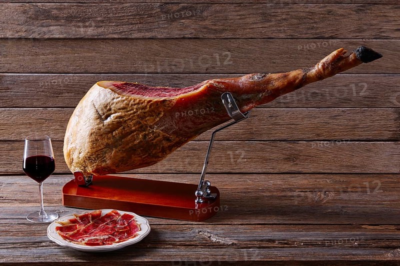 Iberian ham pata negra from Spain with red wine on wood background