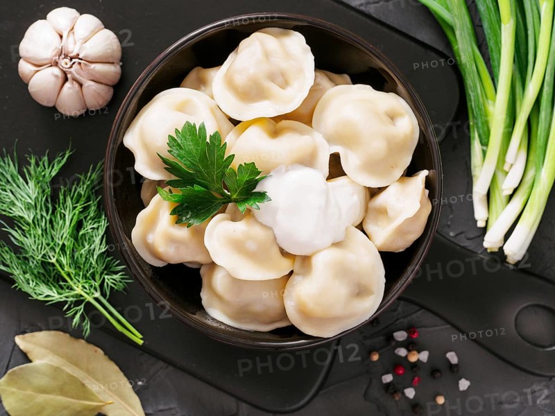 Traditional russian pelmeni, ravioli, dumplings with meat on black concrete background. Top view or flat lay. Russian food and russian kitchen concept