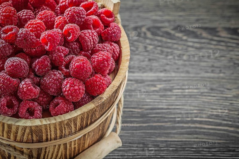 Raspberries in bucket on vintage wooden board horizontal image