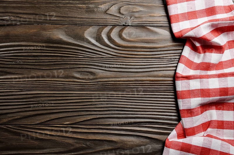 Red checkered napkin on brown wooden kitchen table with copy-space. Top view