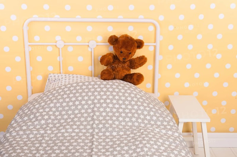 Bedroom with teddy bear sitting on bed