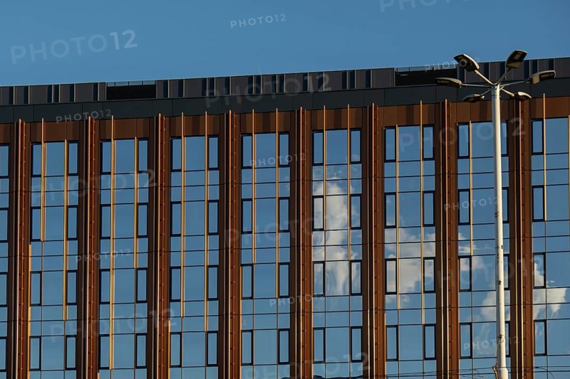 Modern office building exterior with glass facade on clear sky background. Transparent glass wall of office building with yellow decoration. Element of facade of modern European building Commercial office buildings. Abstract modern business architecture