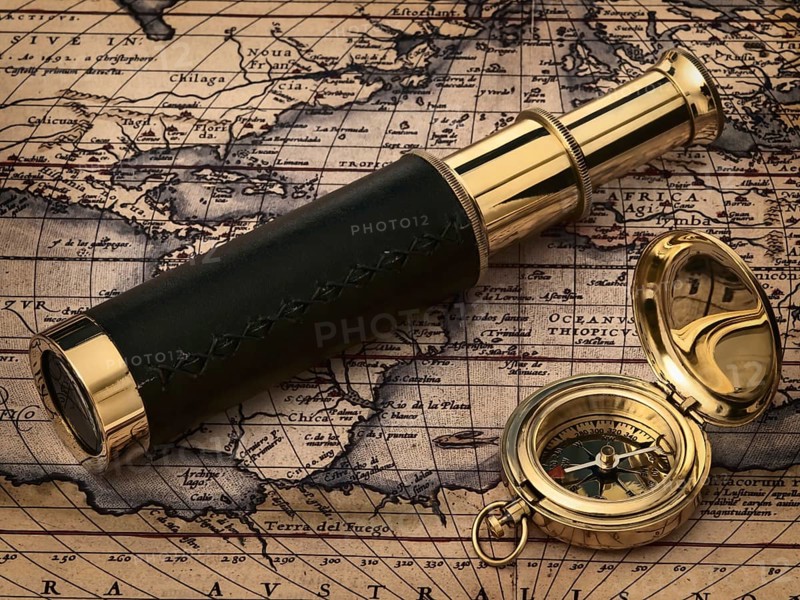 Travelling theme: vintage telescope and compass at antique map