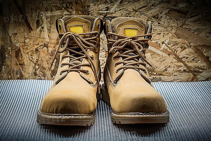 Two brown working boots on plywood background