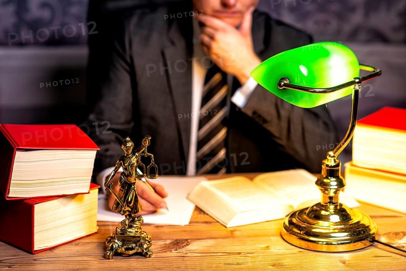 Office of a lawyer with books and a statue of Lady Justice, goddess Justitia, on the desk