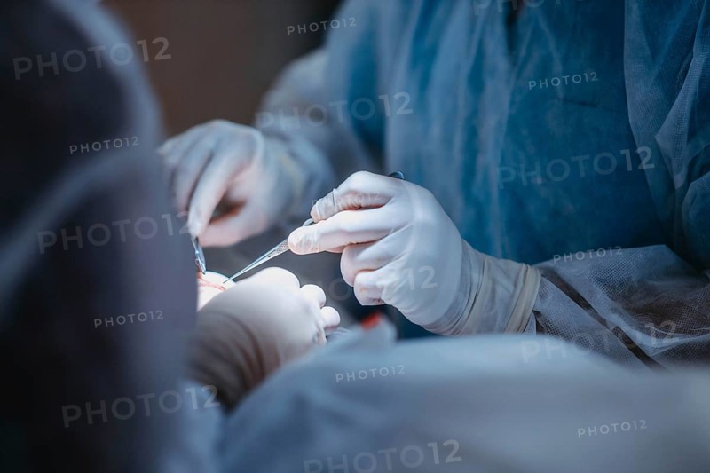 Medical professionals use tools during a surgical operation, emphasizing precision and teamwork