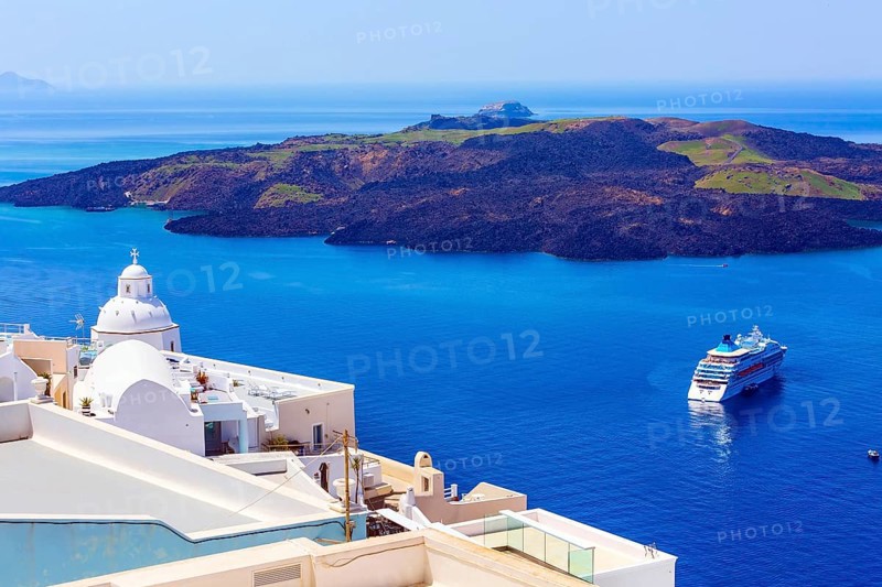 Santorini, Greece iconic view of white houses, church dome, caldera, volcano island and sea panorama with cruise ship