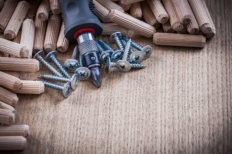 Heap of woodworking dowels stainless construction nails and insulated turnscrew