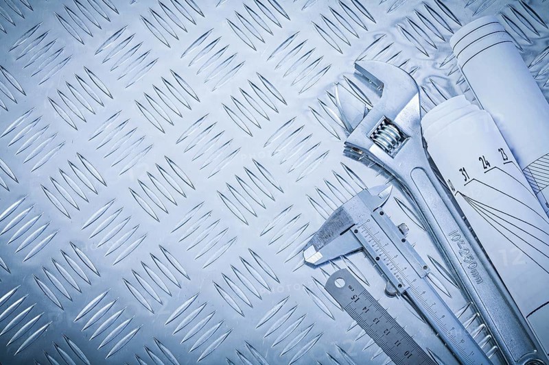 Engineering drawings vernier caliper monkey spanner on channeled metal background construction concept