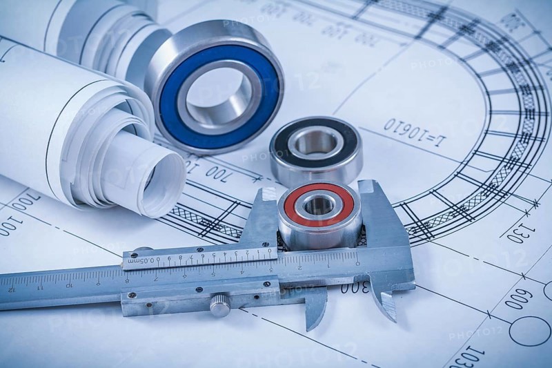 Rolls of construction plans rolling bearings and slide caliper on blueprint industrial concept