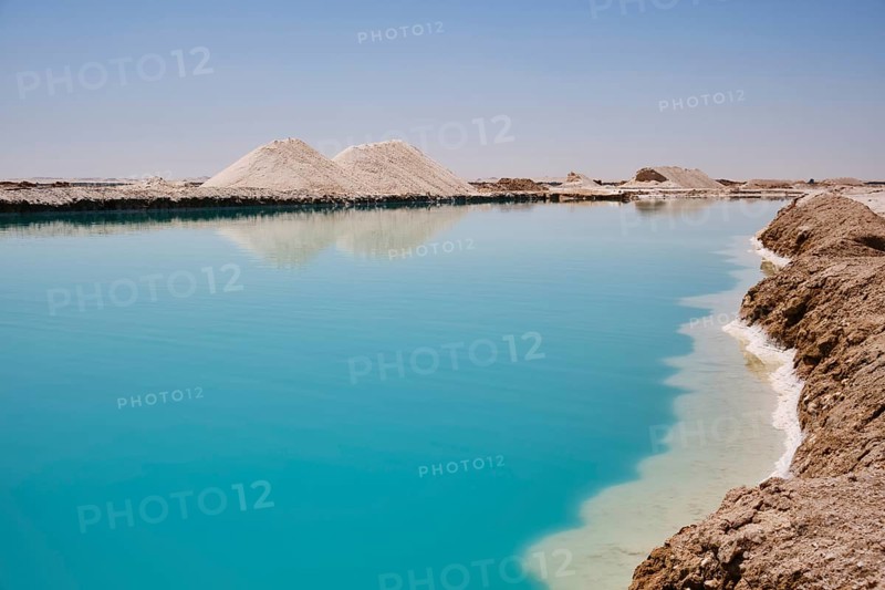 Salt lake with turquoise water and white salt hills on the shore. Siwa oasis, Western Desert, Egypt