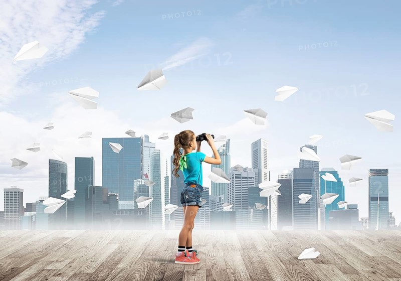 Concept of careless happy childhood with girl looking in binoculars