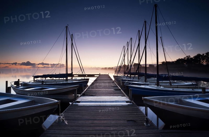 Pier and yacht on lake at sunrise, Netherlands