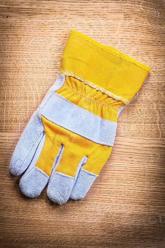 Protective work glove on wooden board construction concept