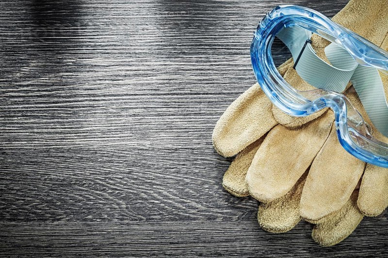 Protective gloves plastic goggles on wooden board