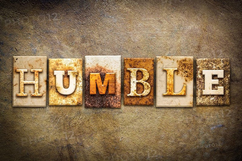 The word HUMBLE written in rusty metal letterpress type on an old aged leather background