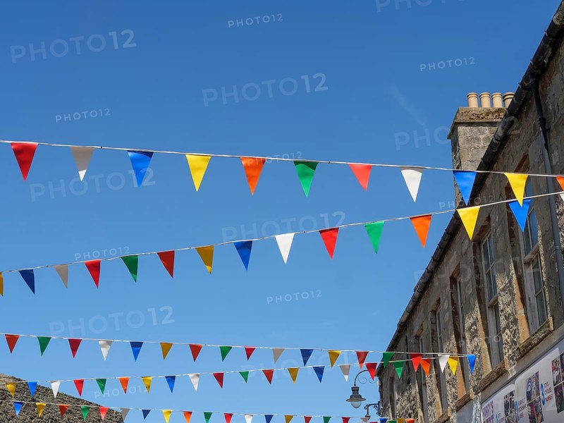 Colourful flags hang over a street corner between historic buildings under a cloudless blue sky, Lerwick, Shetland, Scotland, United Kingdom