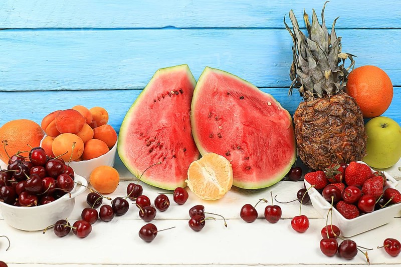 Summer berries and fruits on wooden background, healthy natural food concept, breakfast with ingredients, top view, advertisement for a store, business card for a cafe, invitation with place for text, selective focus