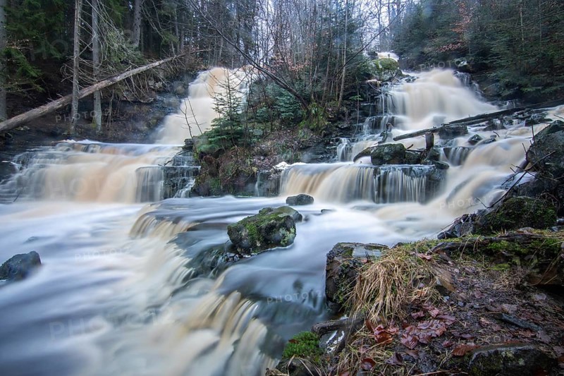 Landscape shot of a large waterfall in a spruce and birch forest and in nature. Autumn landscape with a river becoming the Byklevsfallet waterfall. Vänersborg, Sweden, Scandinavia
