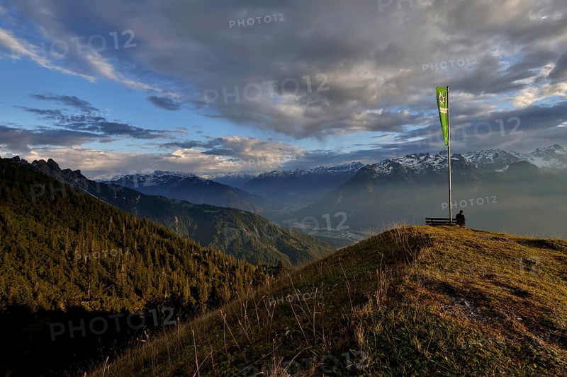 Sitting woman enjoying a dreamlike evening mood in the mountains, view to the Rätikon, flag of the Austrian Alpine Club, Frassenhütte, Vorarlberg, Austria